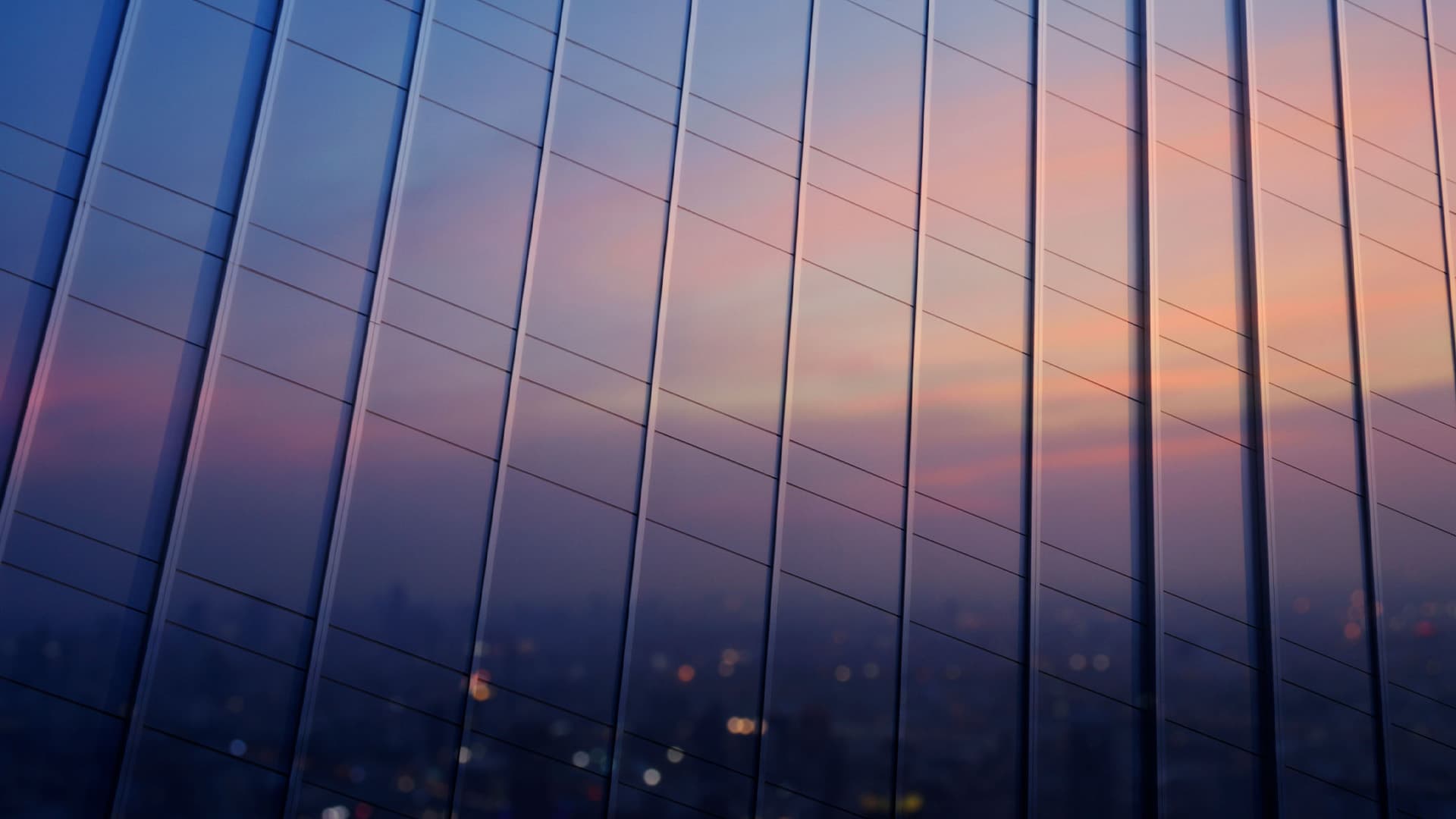 A setting sun reflecting off the mirrored windows of modern high rise buildings.