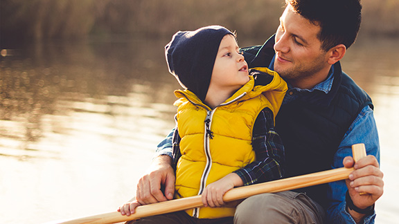 A father and his young son canoeing together on a lake.