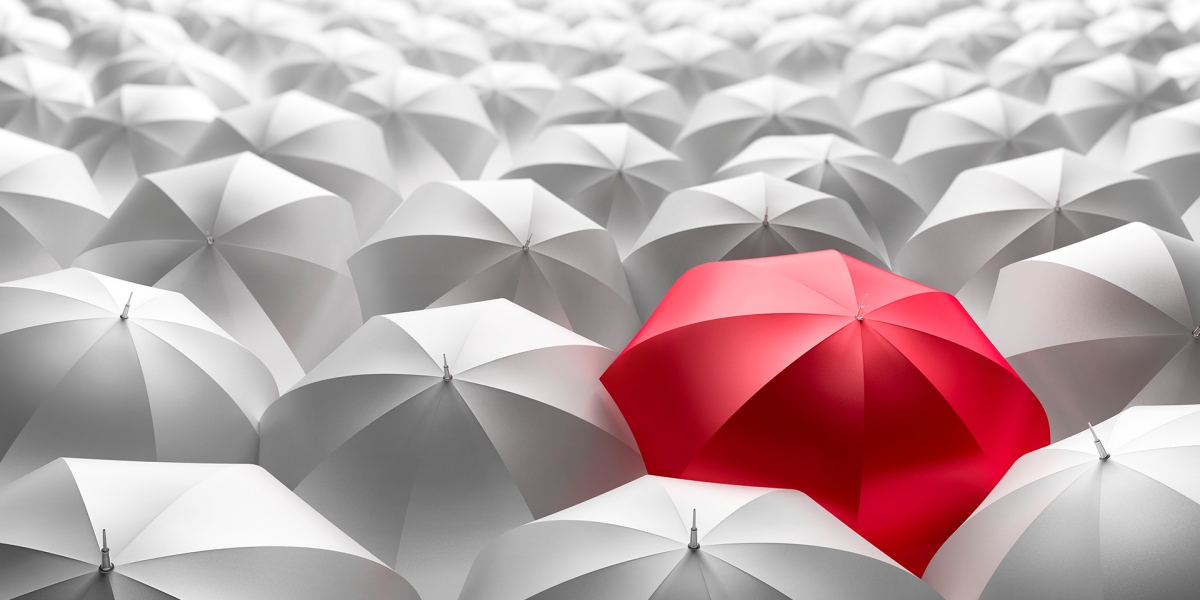 Red umbrella surrounded by grey umbrellas