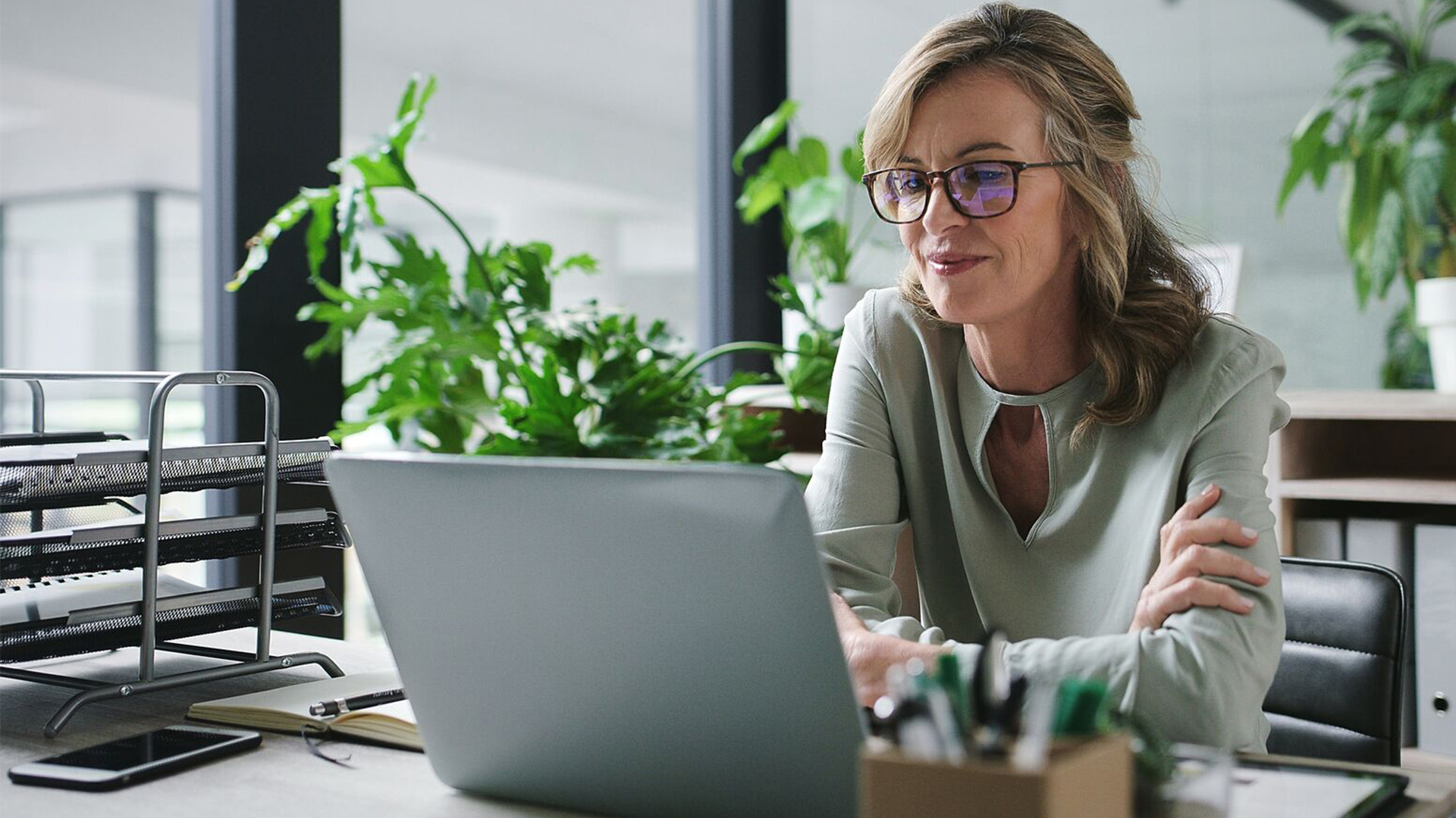 A woman working on her laptop in a bright office.