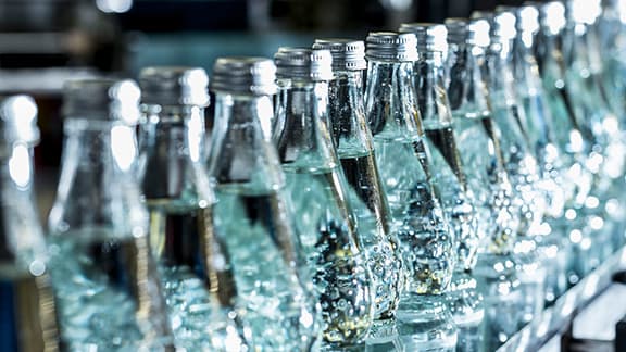 A row of mineral water bottles on conveyor belt.