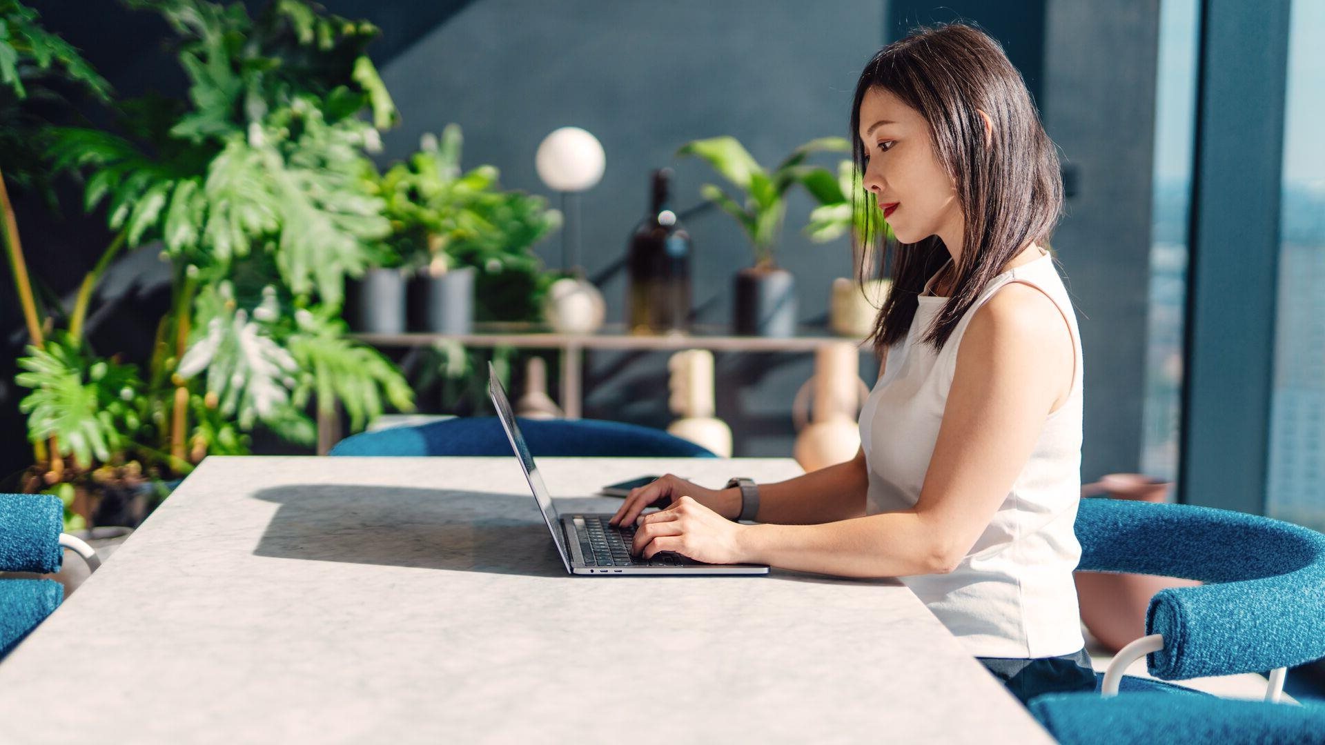 A women working on a laptop while sitting at a desk in an office