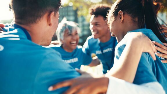 A group of people huddled together for support of a charity or nonprofit