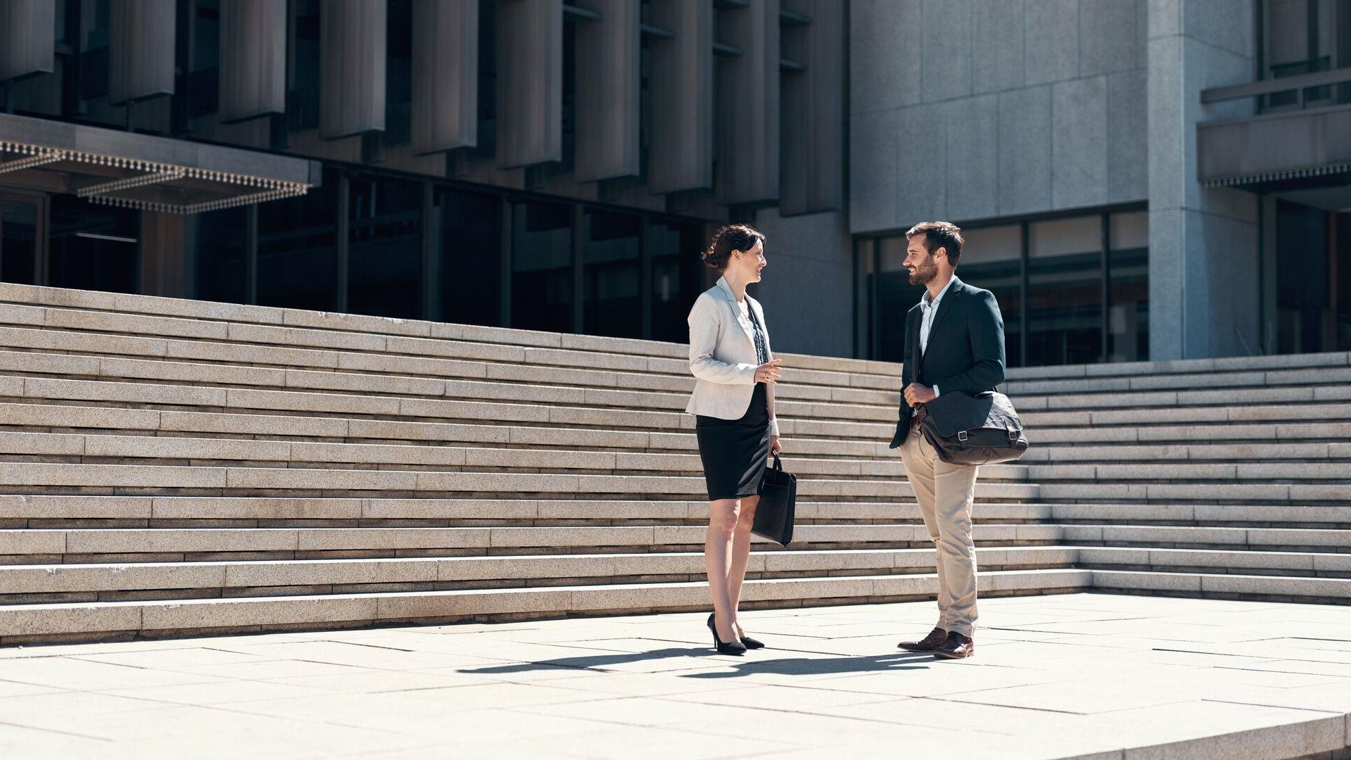 Two work colleagues chatting near outdoor steps.