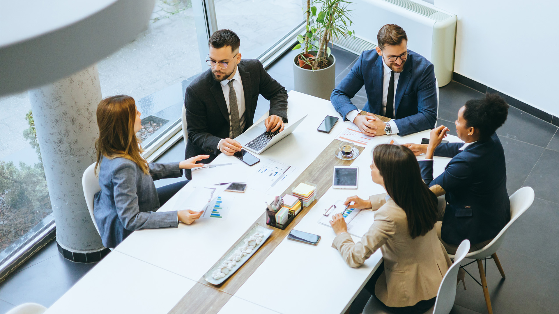 A group of colleagues sitting around a table in an office and talking with each other. 