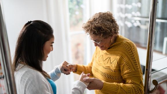 A nurse who is helping a senior patient walk around her home