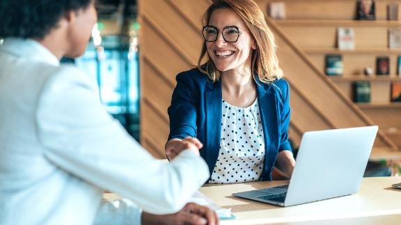Two smiling people shaking hands during a business meeting.
