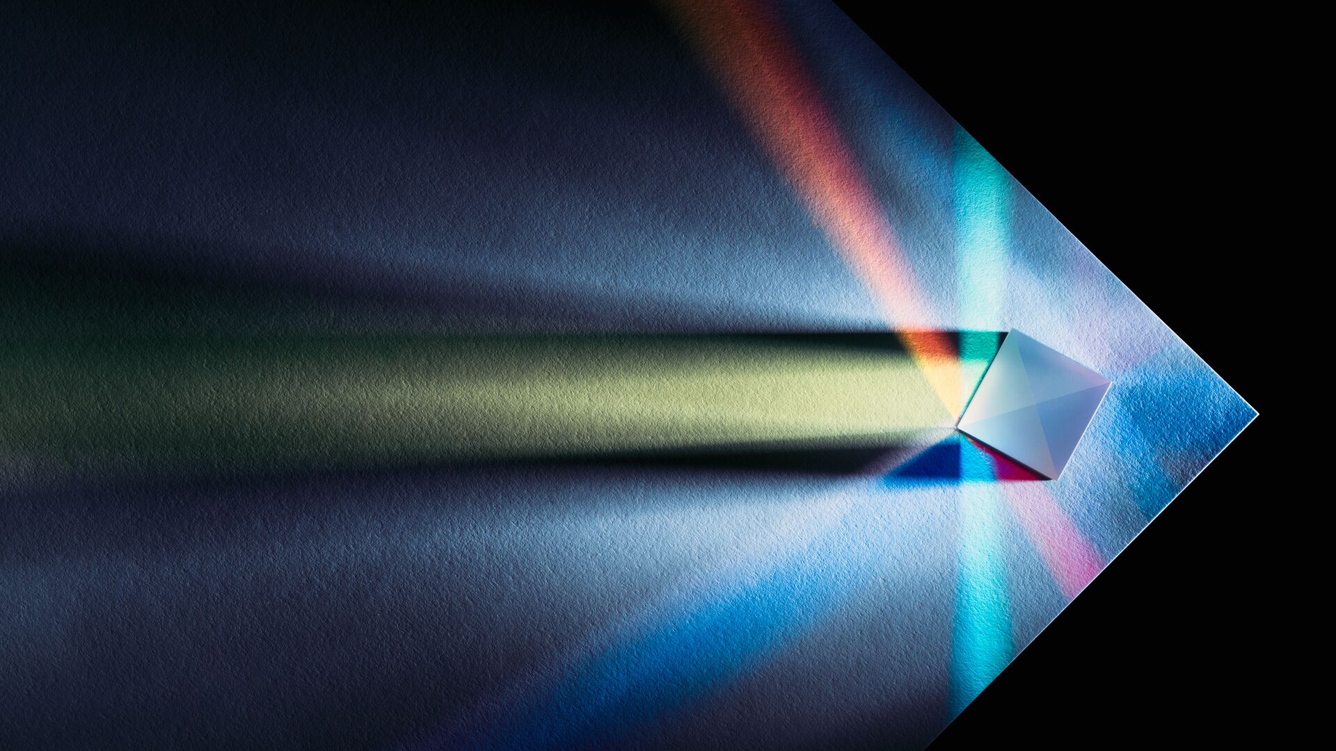 A prism multi-colored refraction on the edge of white paper.