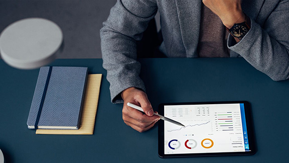 A man looking at stats on a tablet at a desk.