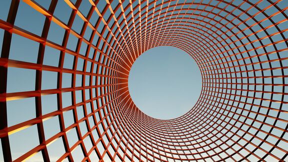 A circular red-orange metal lattice curves upward around a large central opening against a blue sky.