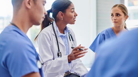 A doctor who is having a team meeting with her nursing staff