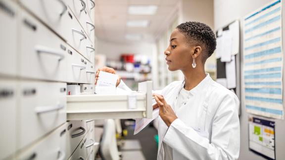 A female pharmacist selecting a medication to fulfill a prescription.