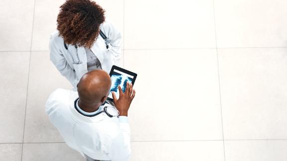 Two doctors looking down at a digital tablet showing the x-ray of a patient