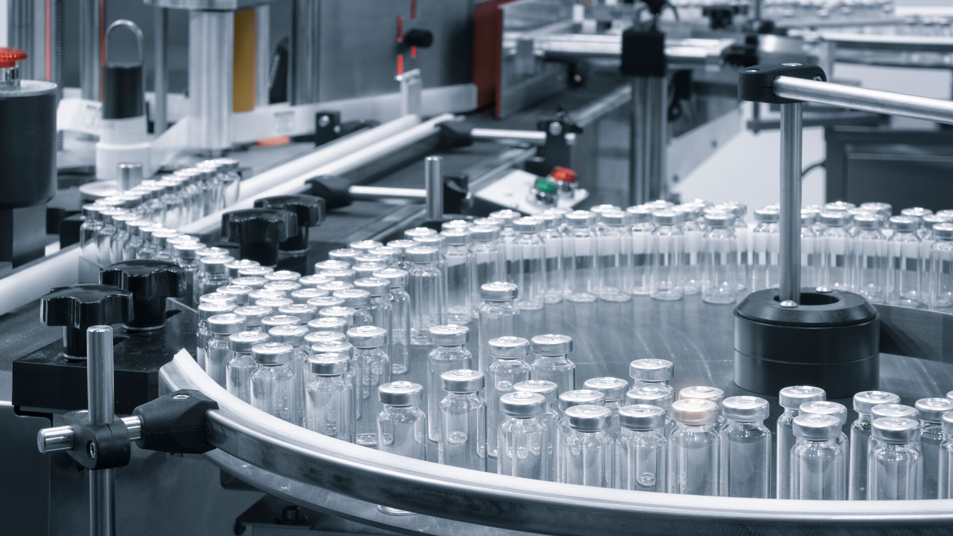 Pharmaceutical industry production line machine conveyor with glass bottles ampoules at factory.
