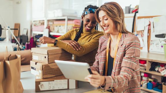 Two women smiling together while working in a retail job.
