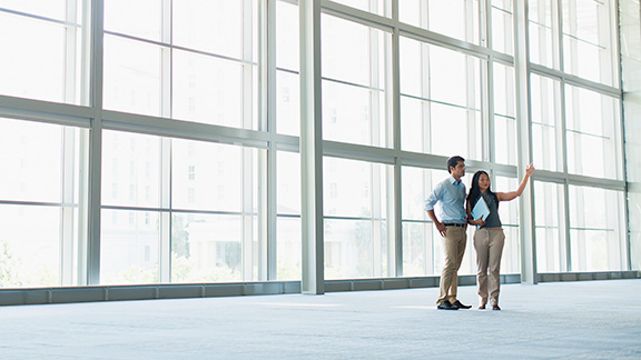 Two people standing and talking together in a large room.