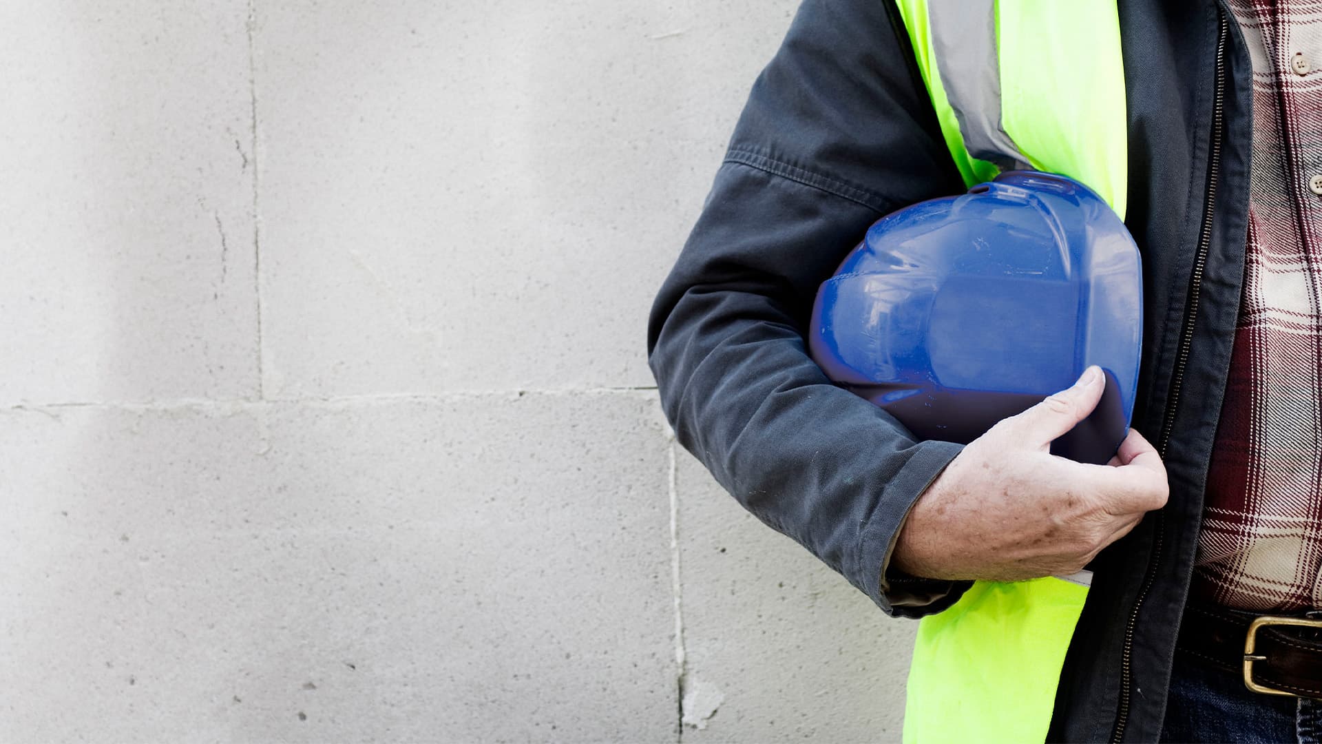 A construction worker holding a hard hat with their right arm