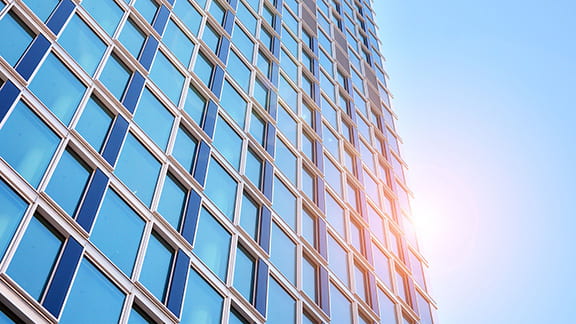 A high rise building with the morning sun reflected off the windows.