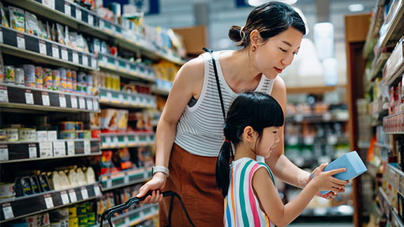 A mother and daughter shopping together at the grocery store.