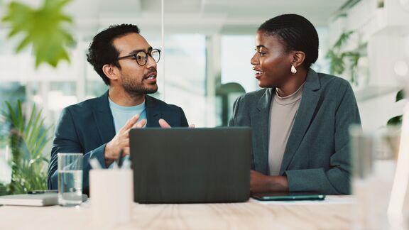 Man and woman having a discussion in front of a laptop.