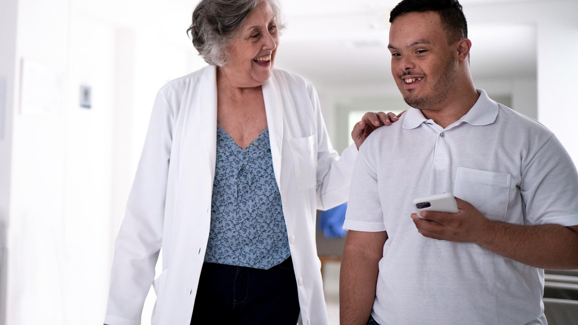 Female senior doctor welcoming / greeting special needs boy at hospital - stock photo