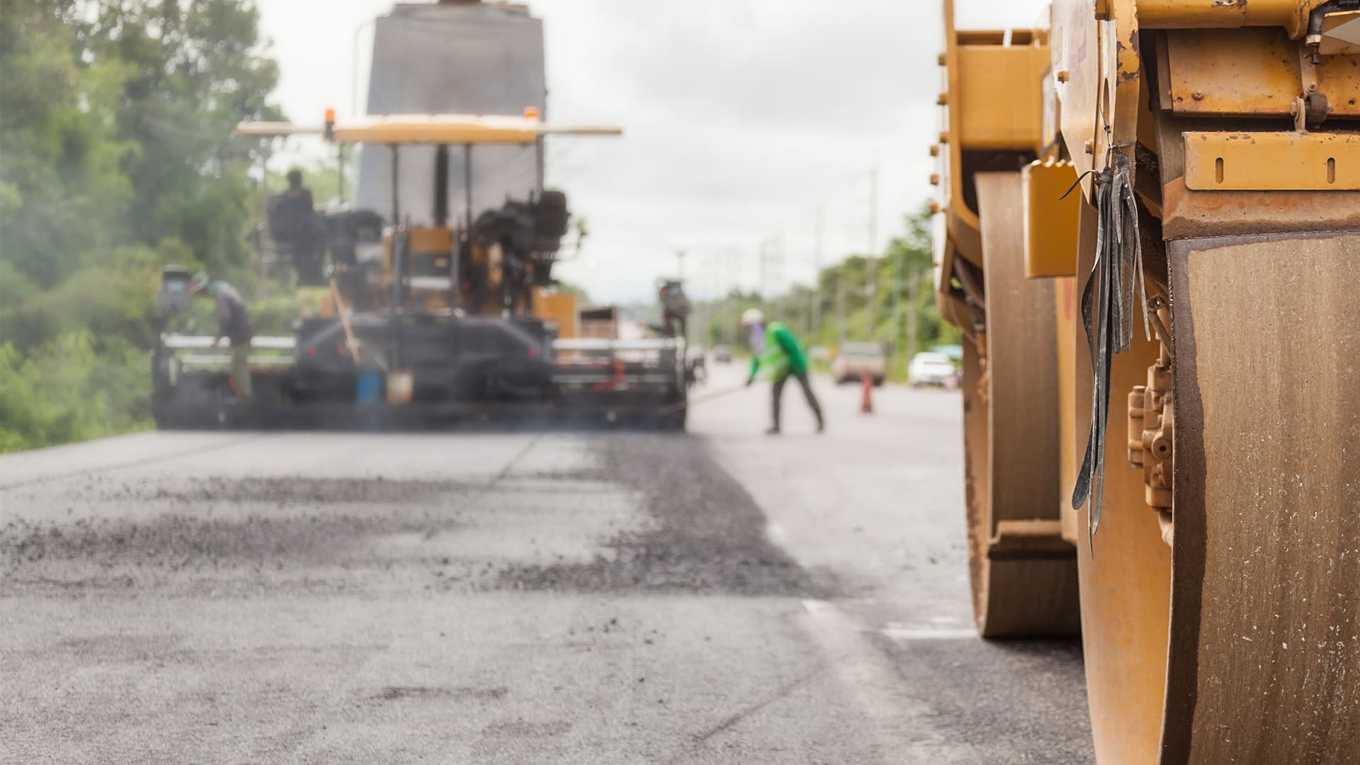 Road construction works with roller compactor machine and asphalt finisher.