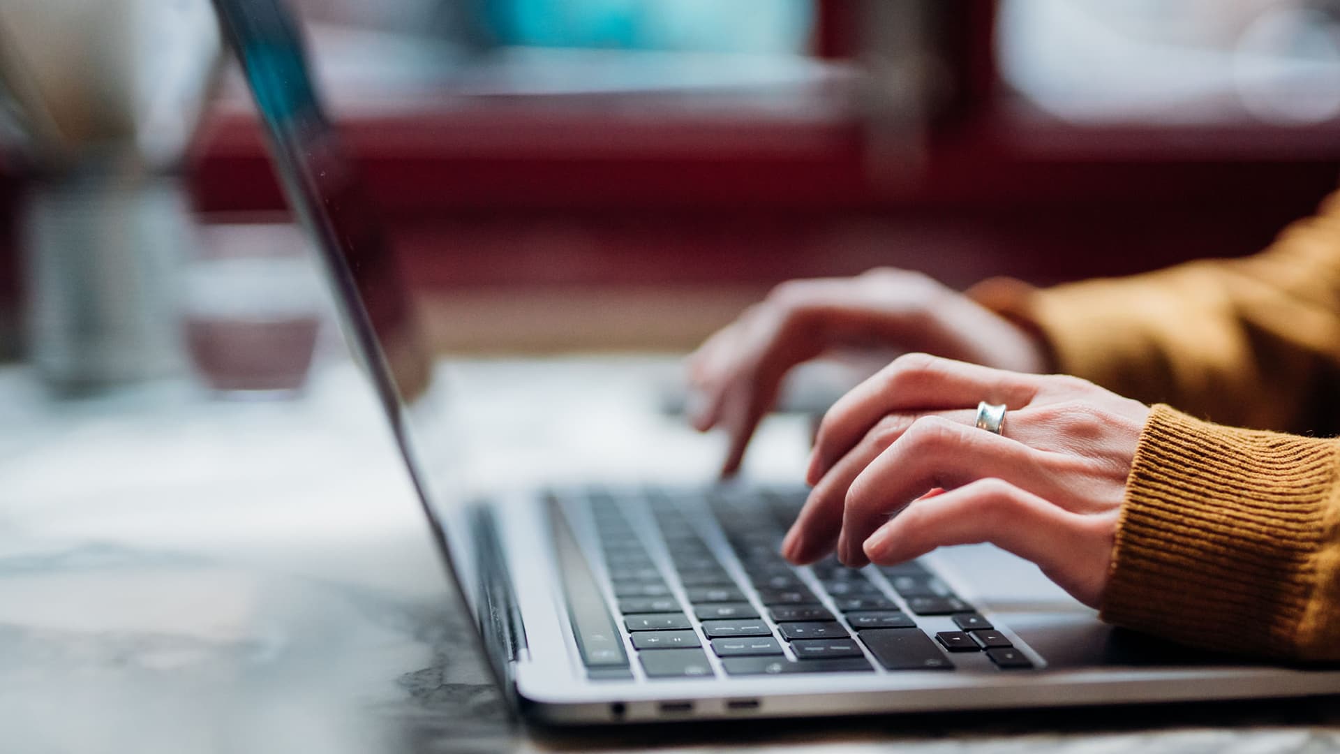 A person typing on their laptop keyboard while sitting at a desk