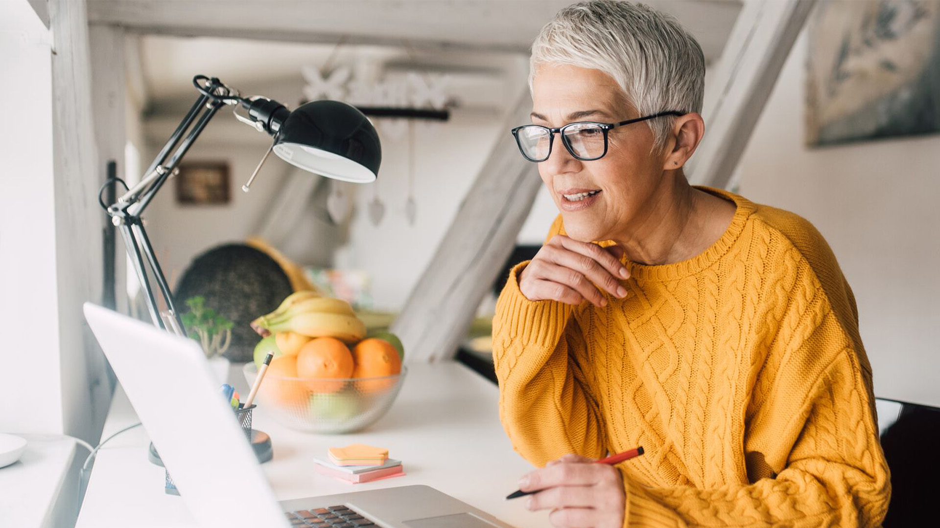 A women who is sitting down at a desk and working on a laptop computer.