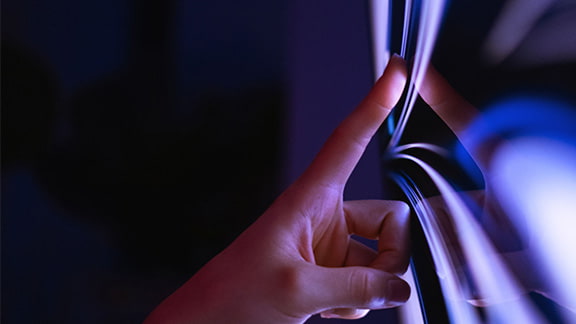 Close up of a pointer finger touching a screen featuring an abstract image.