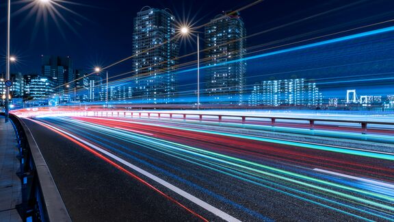 Slow exposure photo of a train going by a city skyline at night.