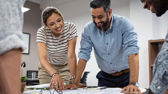 A group of architects working on construction plans in a meeting room.