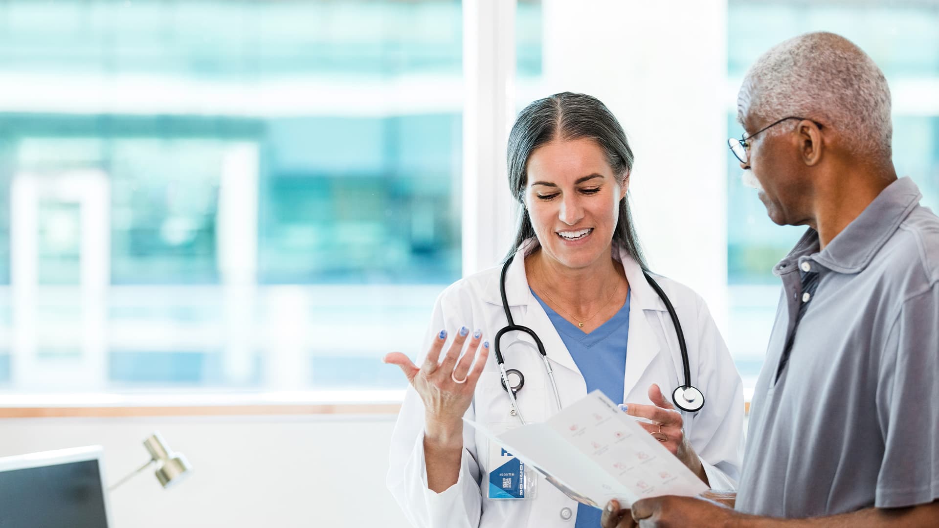 A doctor and senior patient discussing a brochure.