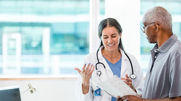 A doctor and senior patient discussing a brochure.
