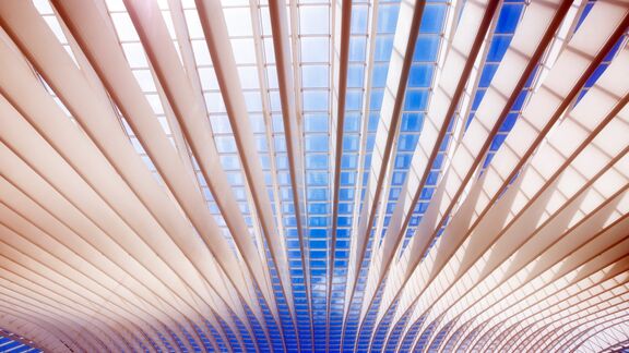 Modern roof of a public transportation building of Liege Guillemins railway station, Belgium, with lights, shadows and sky seen through the glass
