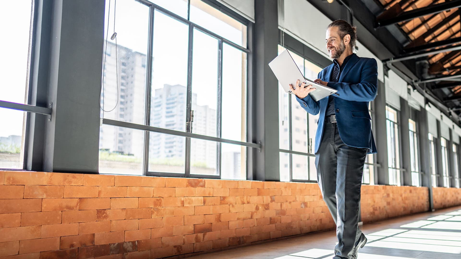 A professional in real estate walks through a building on his laptop.