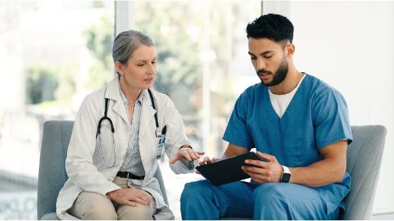 A doctor and a nurse discussing data on a tablet.