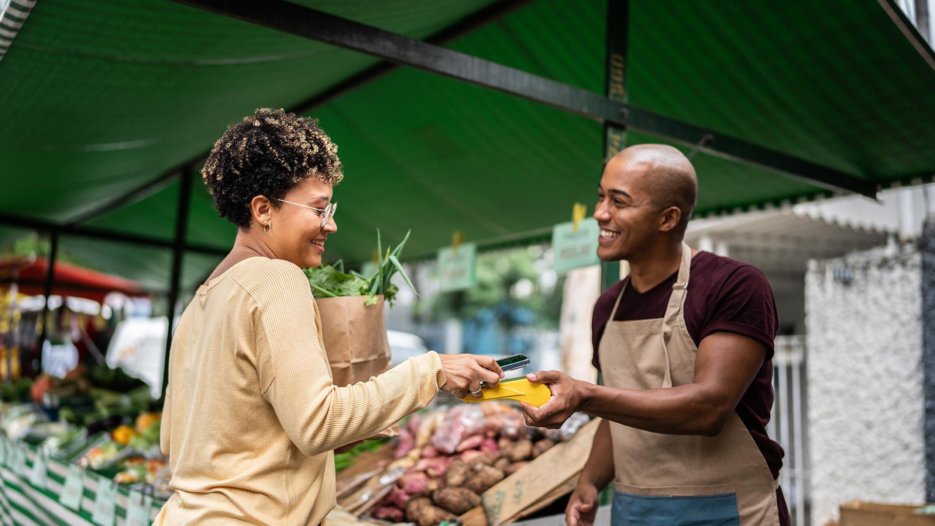 Young woman paying with mobile phone at a street market