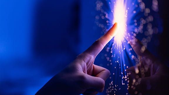 A person pointing at a glowing touch screen.
