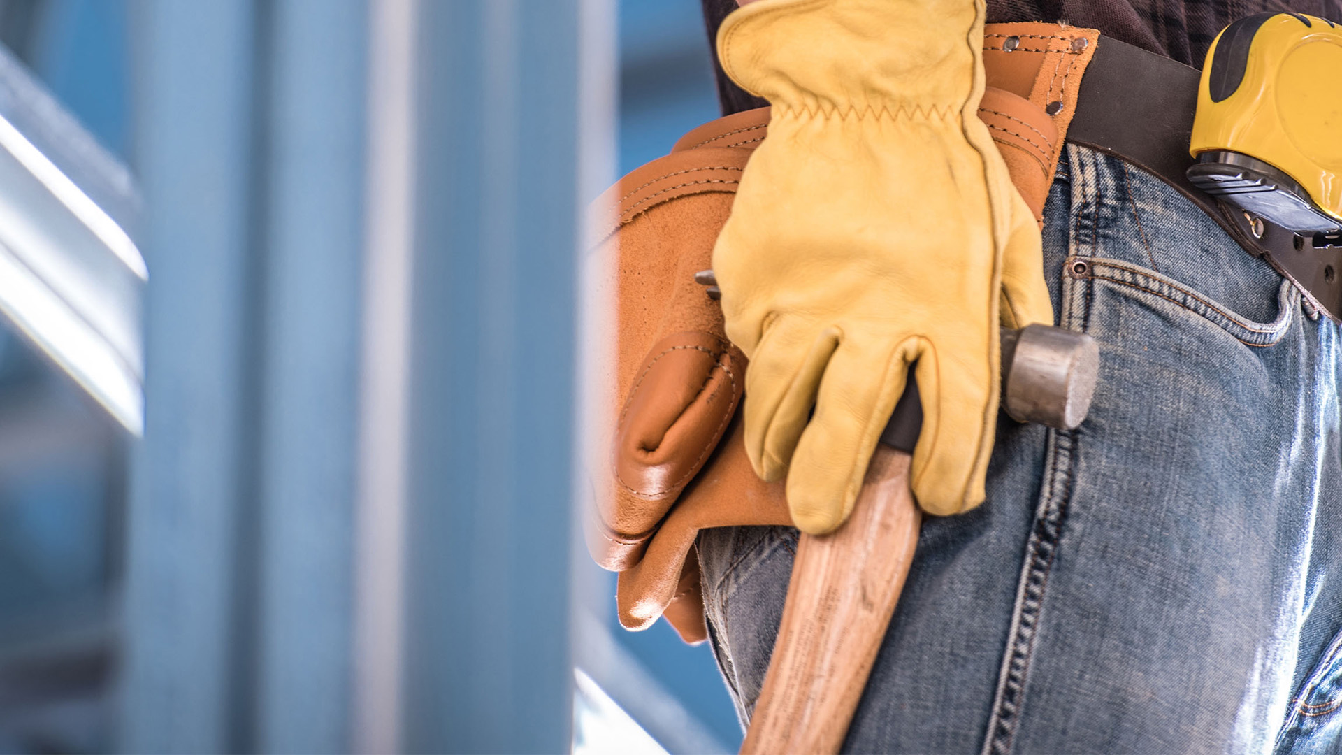 A person wearing a flannel, jeans, gloves and a belt with construction equipment