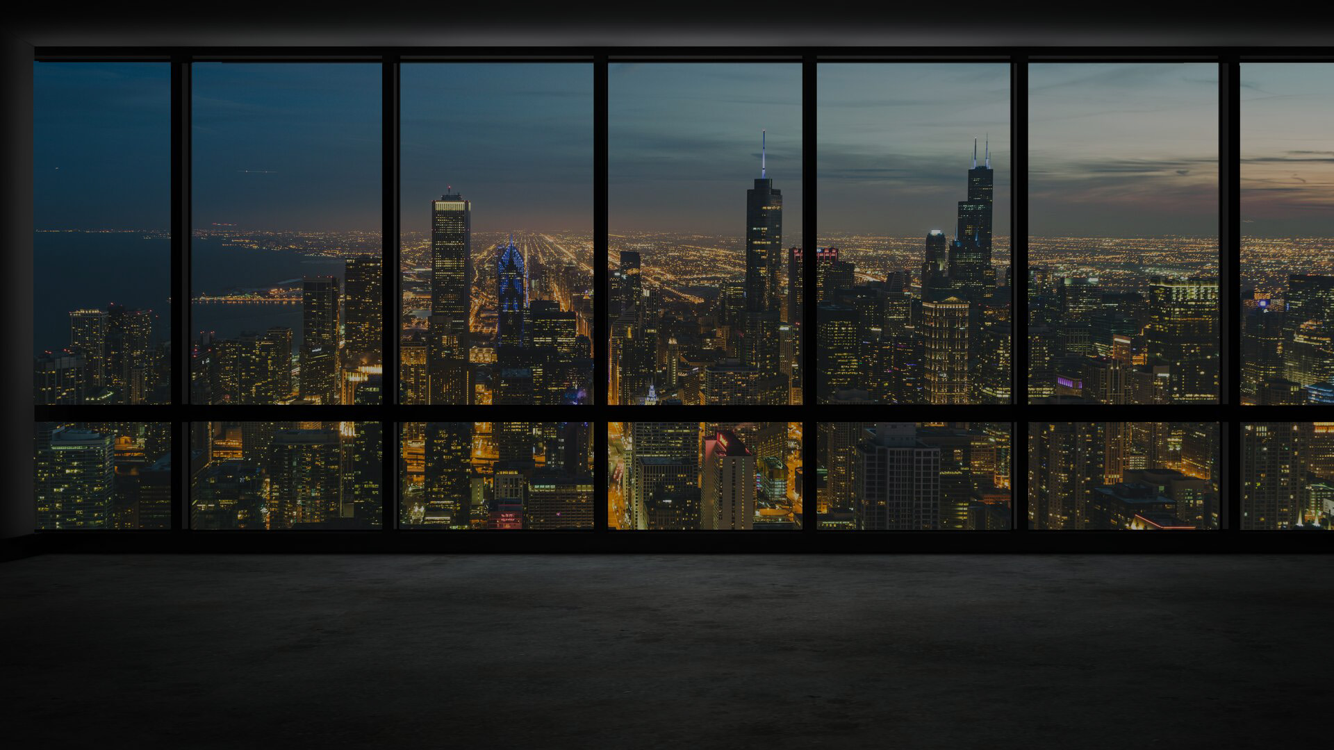 Modern room with floor to ceiling windows overlooking night time city skyline.