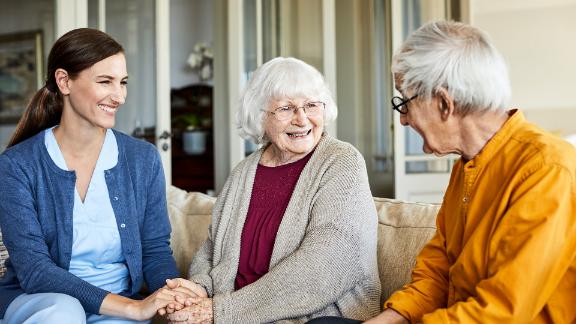 A senior couple speaking with a home health nurse.