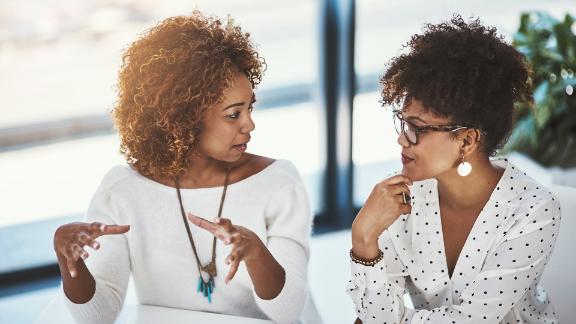 Two women who are seated and having a conversation with each other