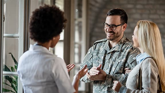 Happy military man and his wife talking to a doctor at medical clinic.