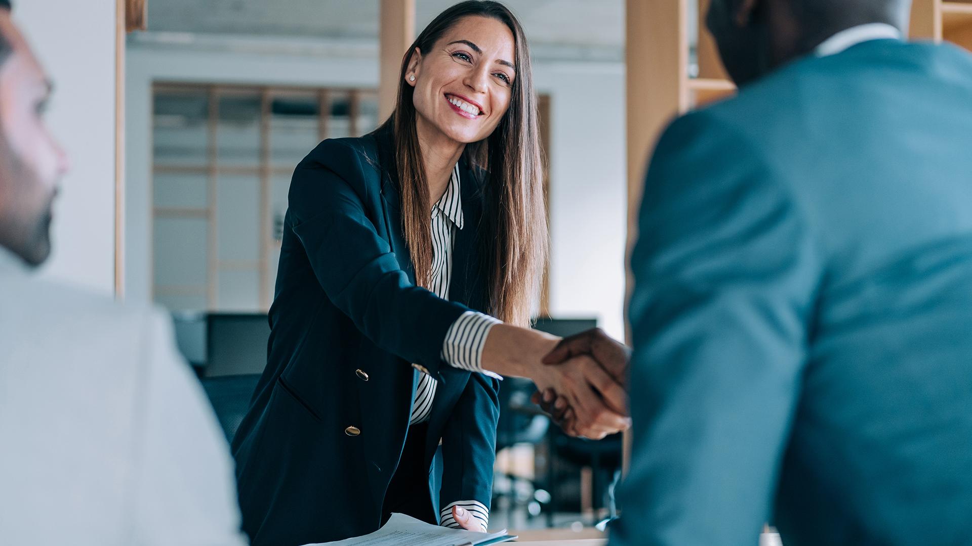A woman shaking hands with a male coworker.