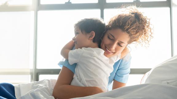 Little boy hospitalized in the pediatrics ward hugging young nurse.