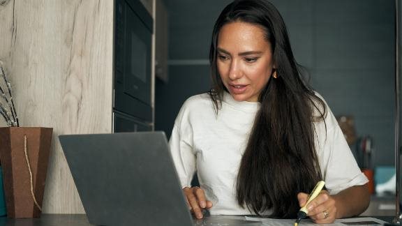 A woman at her desk looking at her laptop.