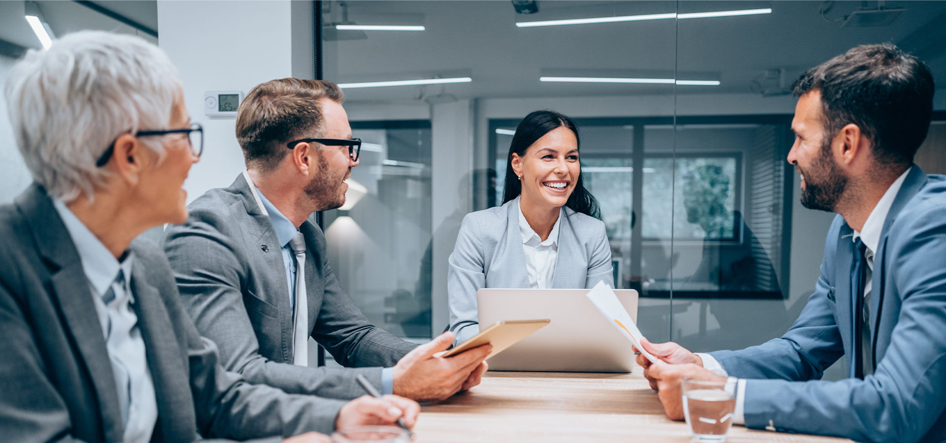 A group of smiling people who are having a business meeting in a boardroom.