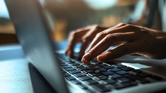 A person typing on their laptop keyboard