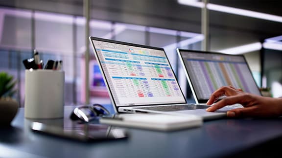 A person using a laptop to calculate electronic medical accounts and codes in an office