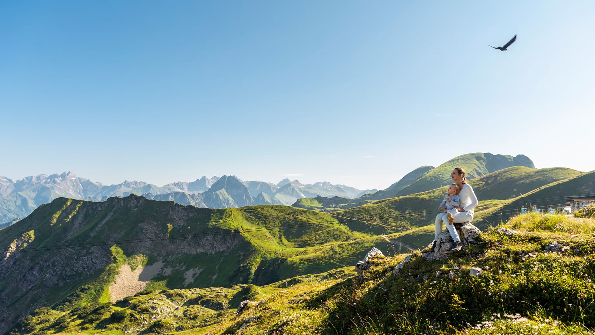 Germany, Bavaria, Oberstdorf, mother and little daughter on a hike in the mountains having a break looking at view 